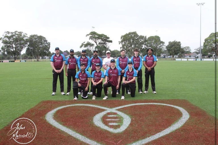 Sports team posed on field with heart logo, wearing red and blue uniforms, standing on diamond infield
