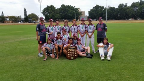 Youth sports team posing with trophy and medals on grass field after winning championship